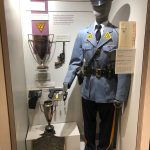 Uniformed police mannequin display with medals, historical photo, and informational plaques.