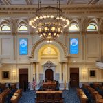 Ornate, grand chamber with high ceilings, chandeliers, and seating for a formal assembly.