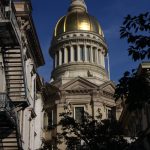 Golden dome of a historic building against a deep blue sky, framed by surrounding architecture and trees.