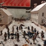 Miniature army battle scene set in a snowy, village-like diorama.