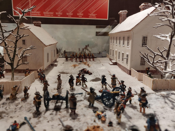 Miniature army battle scene set in a snowy, village-like diorama.