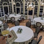 Elegant dining room with white tables, chairs, and large arched windows.