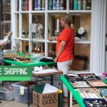 Woman shops at a boutique window display, browsing jewelry and goods.