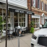 Cafe facade with "Chez Alice Patisserie" sign, outdoor seating area, and white SUV parked nearby.