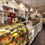 Bakery display case filled with cakes, pastries, and sweets in a bright shop interior.