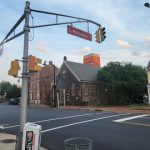 Street intersection with historic buildings, traffic light, and cloudy sky.