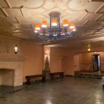 Ornate ceiling and grand chandelier in a spacious, warmly lit interior hall.