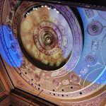 Ornate, gilded theater proscenium arch with intricate gold and blue decorative molding.