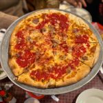 Pepperoni and sausage pizza with tomato sauce on a metal tray.