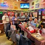 Group of women gathered in a lively bar setting, posing for a photo.