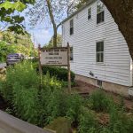 Historic white house near a canal, with a sign marking "Port Mercer Canal House."