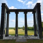 Ancient stone temple ruins with tall columns under a blue, cloudy sky.