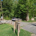 Outdoor area with wooden gates, trees, and a sign advertising open canoes and kayaks.