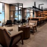 Modern hotel lounge with comfortable seating, dining area, and large windows.