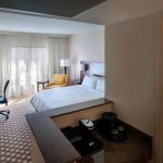 Modern hotel room with a large bed, window view, and desk area.