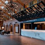 Industrial lobby with high wooden ceiling, brick walls, and marble reception desk.