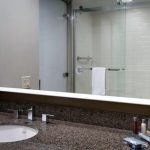 Modern bathroom vanity with sink, granite countertop, and glass shower enclosure.