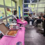 Children and adults gather in a bright room with play equipment visible in the background.