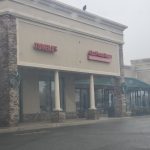 Tumbles storefront with columns and signage on a cloudy day.