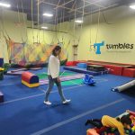 Indoor play area with climbing nets, blue flooring, and children playing.