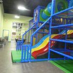 Colorful inflatable playground structure with blue railings in a bright indoor facility.