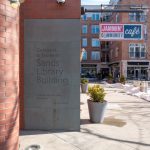 Exterior view of the Sands Library Building with a modern brick facade and cafe signage.