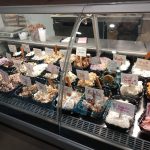 Assortment of gourmet ice cream and dessert cups displayed in a refrigerated case.