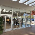 Modern storefront with large glass windows showcasing a boutique interior and outdoor walkway.