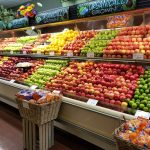Abundant display of fresh, colorful fruits like apples and oranges in a grocery store.