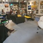 Musicians and people gather in a bright, open retail space with art on the walls.