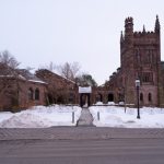 Gothic university buildings stand against a winter sky with snow on the ground.