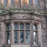 Stone facade with arched windows and carved decorative elements on an old building.