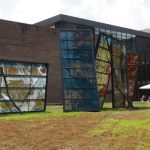 Large, colorful abstract metal sculptures displayed outside a modern brick building.