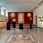 Ancient artifacts displayed in a museum hall with a large mosaic floor.
