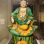 Jade-green seated Buddha statue with elaborate crown and golden orb on a detailed base.