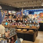 Shop interior displaying various candles, home goods, and artisanal products on wooden shelves.