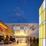 Quaker Bridge Mall exterior at twilight, featuring modern architecture and illuminated signage.