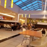 Bright, modern mall interior with a glass atrium and seating areas.