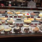 Display case filled with various cakes, pastries, and desserts in a bakery.