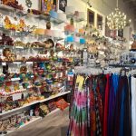 Shop display featuring shelves of trinkets and racks of colorful clothing.