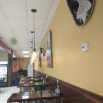 Interior view of a restaurant with yellow walls, dark wood paneling, and artwork.