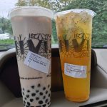 Two iced drinks, one milk tea and one fruit tea, sitting in a car.