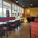 Restaurant interior with large windows, booths, and dining tables.