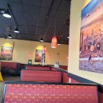 Restaurant interior with booth seating and a large mural on the wall.