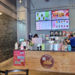 Modern noodle shop interior with stone wall, digital menu boards, and counter service.