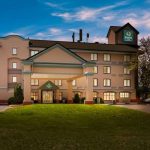 Quality Inn hotel building under a bright blue sky with green lawn in foreground.