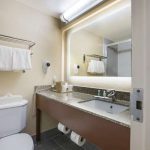 Bathroom vanity with mirror, sink, and toilet in a modern hotel room.