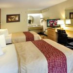 Two queen beds with patterned runners in a bright hotel room.