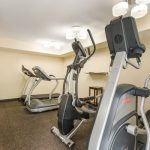 Gym interior with several cardio machines, including treadmills and elliptical trainers.