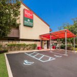 Red Roof Inn hotel entrance with covered parking and accessible spots under a red awning.